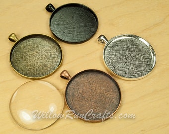 May include: Five round metal pendant trays in different finishes: black, antique brass, silver, copper, and clear glass. The trays have a textured surface and a loop for hanging.