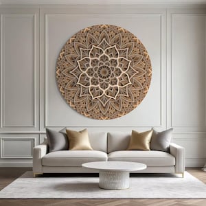Könnte beinhalten: Ein großes, rundes Wandkunstwerk mit Mandala-Motiv aus Holz mit einem geschichteten Design hängt über einem cremefarbenen Sofa. Der Raum hat eine neutrale Farbpalette mit einem Teppich, einem Couchtisch und dekorativen Kissen.