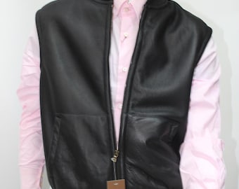 May include: A black leather vest with a zipper closure. The vest has a  ribbed collar and a  tag that says "Genuine Leather" on the front. The vest is being worn by a mannequin with a pink shirt and black pants.