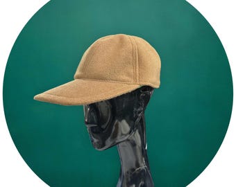 May include: A tan baseball cap with a curved brim. The cap is made of a soft, textured material and has a classic six-panel design. The cap is displayed on a black mannequin head against a teal green background.