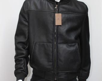 May include: A black leather bomber jacket with a zipper closure and a black and white plaid newsboy cap.