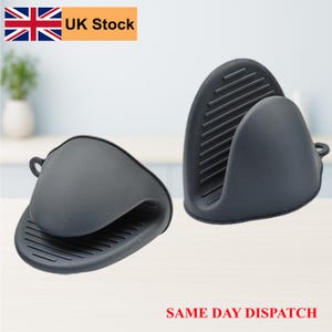 May include: Two dark grey silicone oven mitts. Each mitt has a loop for hanging and a textured surface for grip. The mitts are designed to protect hands from heat when handling hot cookware. The text "UK Stock" is visible in the image.