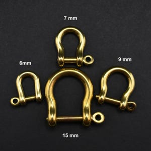 May include: Four gold-coloured metal rings with a pin closure. The rings are different sizes: 6 mm, 7 mm, 9 mm, and 15 mm.