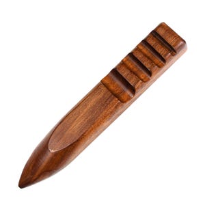 May include: A wooden tool with a pointed end and a series of ridges along the top. The tool is brown and has a smooth, polished finish.