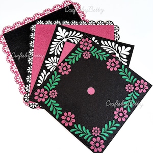 Könnte beinhalten: Ein Stapel dekorativer quadratischer Papierauschnitte. Der obere Ausschnitt ist schwarz mit einem rosa gewellten Rand. Die nächste Schicht ist rosa mit weißen floralen Designs. Der untere Ausschnitt ist schwarz mit rosa Blumen und grünen Blättern.