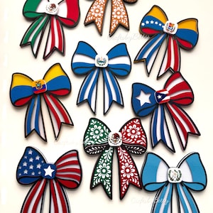 Puede incluir: Una colección de lazos decorativos con las banderas de varios países. Cada lazo está diseñado de forma única con colores y patrones vibrantes, incluyendo las banderas de México, Estados Unidos y otros. Los lazos tienen un contorno negro y un pequeño emblema en el centro.