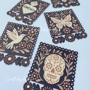 May include: Decorative die-cut paper designs in brown, tan, and peach. The designs include a cross, a butterfly, a dove, a heart with thorns, and a sugar skull. Each design is framed with floral and leaf patterns and scalloped edges.