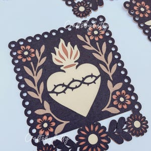 May include: Decorative die-cut paper art featuring a heart with a crown of thorns, surrounded by floral and leaf accents. The design is in shades of brown, beige, and peach, with a scalloped border. The theme is religious or spiritual.