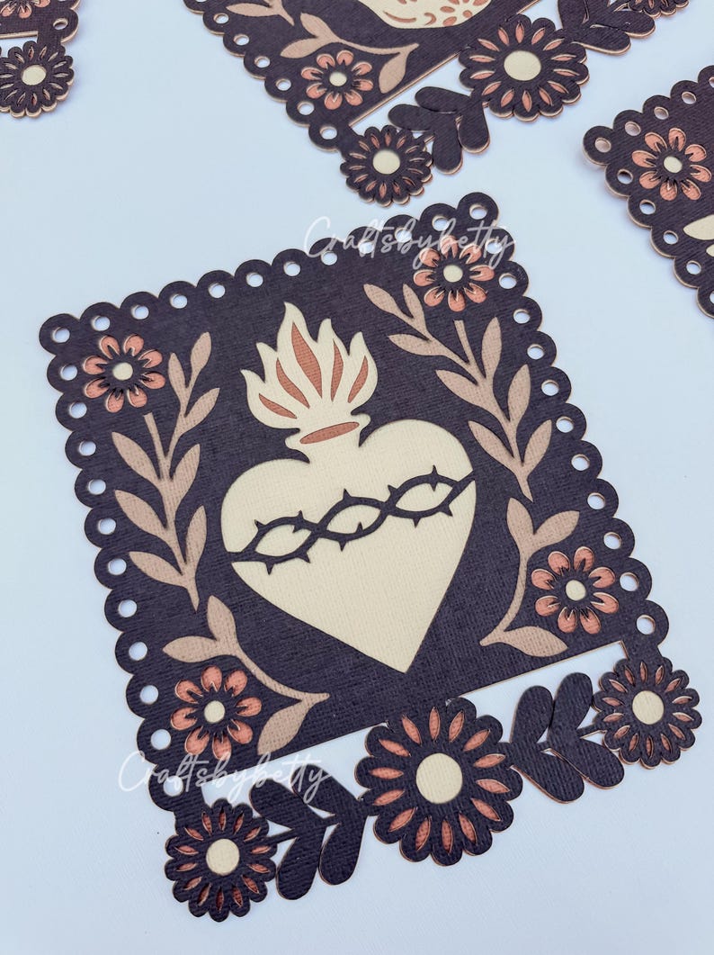May include: Decorative die-cut paper art featuring a heart with a crown of thorns, surrounded by floral and leaf accents. The design is in shades of brown, beige, and peach, with a scalloped border. The theme is religious or spiritual.