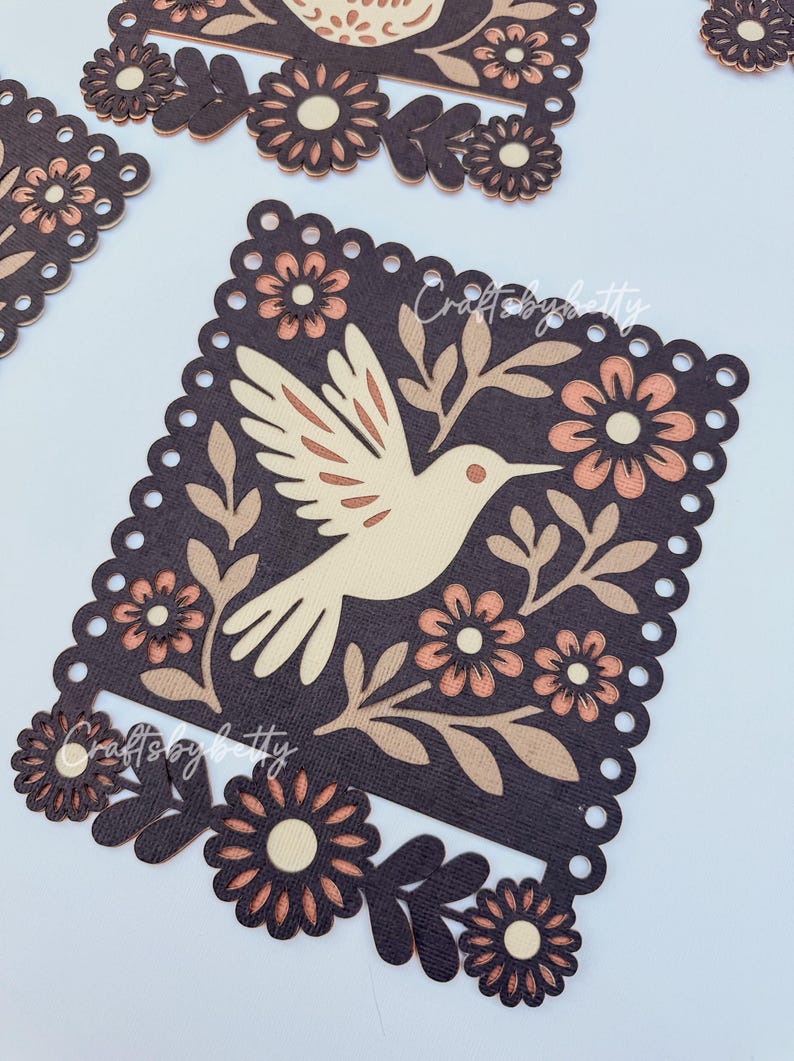 May include: Laser-cut wooden decorative pieces featuring a bird and floral design. The bird is light beige, surrounded by brown leaves and peach-colored flowers, set against a dark brown background. The edges have a scalloped design. The text "Crafts by betty" is visible.