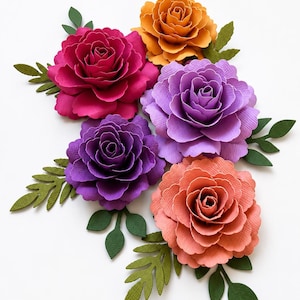 Op de afbeelding: Een verzameling van vijf gelaagde papieren bloemen in de kleuren magenta, oranje, lavendel, paars en koraal. Elke bloem heeft ingewikkelde, getextureerde bloemblaadjes en wordt vergezeld door verschillende donkergroene papieren bladeren met nerven.