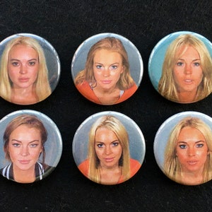 May include: Six round buttons with a photo of a woman with blonde hair. The woman is wearing an orange jumpsuit. The buttons are all the same size and have a white background.