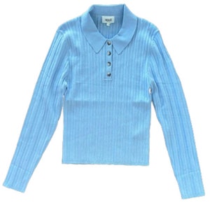 Pode incluir: Uma camisa de manga comprida de malha canelada azul claro com gola e fecho de botões. A camisa tem uma etiqueta 'seed' na gola.
