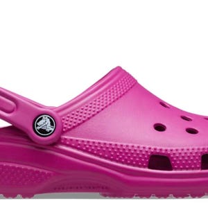 May include: A pair of pink Crocs clogs with a back strap. The clogs have a textured sole and a small logo on the strap.