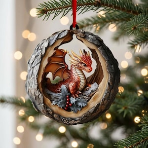 May include: A round Christmas ornament featuring a red dragon with wings perched inside a textured, wood-like frame. The dragon sits among green holly leaves and red berries. The name William is printed in white script at the bottom of the frame.