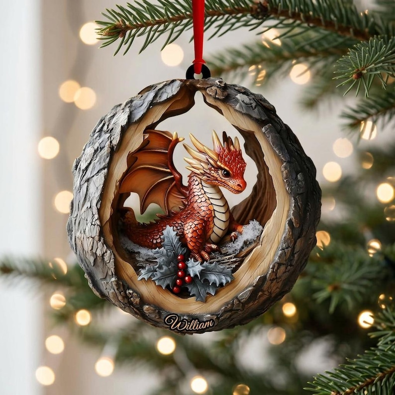 May include: A round Christmas ornament featuring a red dragon with wings perched inside a textured, wood-like frame. The dragon sits among green holly leaves and red berries. The name William is printed in white script at the bottom of the frame.