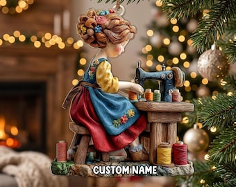 May include: A hanging ornament featuring a figure with auburn hair styled with colorful flowers, wearing a blue apron over a yellow shirt, sitting on a wooden stool at a sewing machine. The base includes spools of thread and the text CUSTOM NAME.