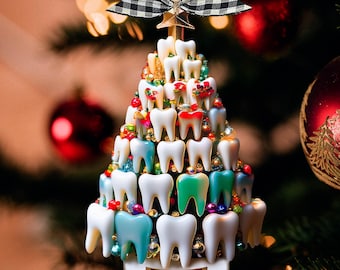 Puede incluir: Un adorno de árbol de Navidad en forma de cono construido con numerosas figuras en forma de dientes blancos y de colores, acentuadas con pequeñas cuentas. Una cinta a cuadros blancos y negros corona la parte superior y una base blanca muestra el texto Dr. Louis.