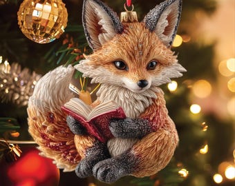 May include: A hanging Christmas tree ornament shaped like a fox with orange and white fur, black paws, and black-tipped ears. The fox is sitting upright and holding an open red book with both paws. The ornament features a red ribbon for hanging.