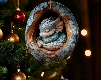 May include: A blue and white sleeping dragon ornament hanging from a Christmas tree. The dragon is curled up inside a tree trunk shaped ornament.