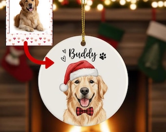 Puede incluir: Adorno navideño redondo de cerámica blanca con un Golden Retriever con gorro de Papá Noel y pajarita a cuadros rojos y negros. El adorno tiene el nombre "Buddy" y una huella de pata. Una foto del perro está en la esquina superior izquierda.