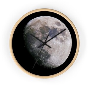 May include: A round wall clock with a black background and a full moon image. The clock hands are black.