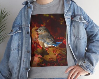 May include: A gray crew neck t-shirt featuring a detailed illustration of a bluebird perched on autumn leaves. The bird has blue wings and a brown body. The leaves are red and yellow.