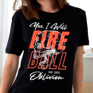 Op de afbeelding: Zwart t-shirt met een witte schedelafbeelding en de woorden "Yes, I Will FIRE BALL You Into Oblivion" in wit en oranje. Het ontwerp toont een gedetailleerde schedelillustratie.