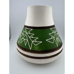 Può includere: Un vaso in ceramica con la parte superiore bianca e una fascia verde con disegni geometrici bianchi. Il vaso ha strisce marroni e bianche vicino alla base. È un oggetto decorativo per la casa.