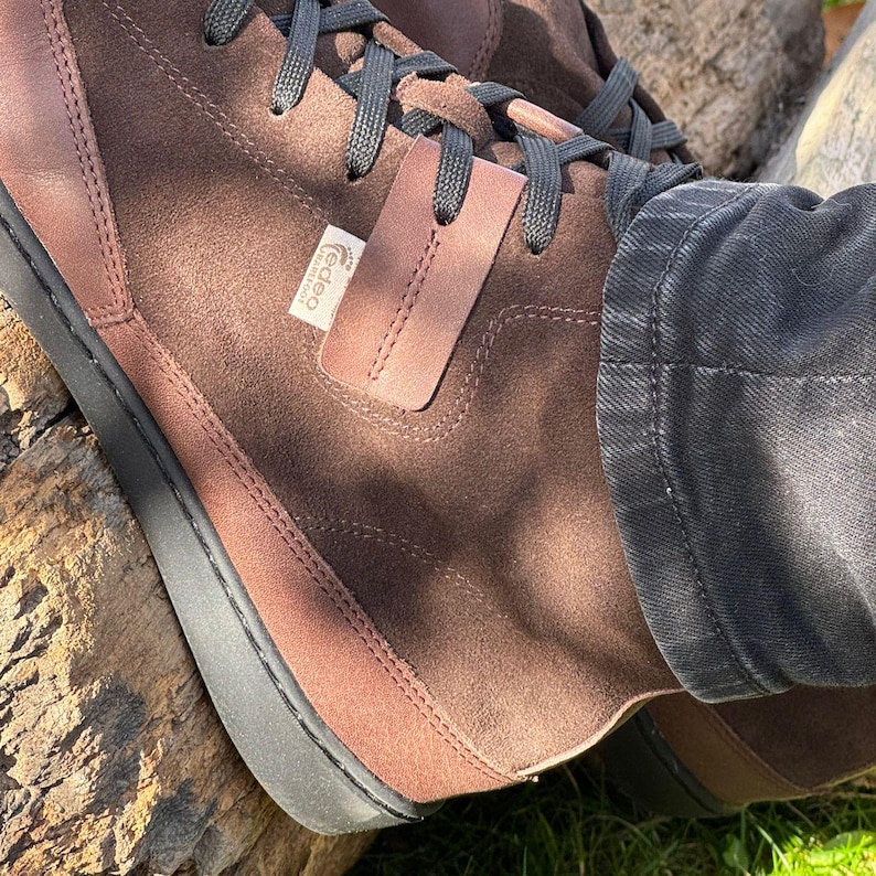 May include: Brown suede high-top sneakers with black laces and a black rubber sole. The brand name "Gadeo" is visible on the side of the shoe.