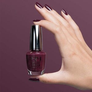 May include: A bottle of OPI Infinite Shine 2 nail polish in a deep burgundy color. The bottle is held by a hand with nails painted in the same color.