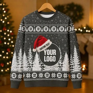 Può includere: Una maglia a maniche lunghe girocollo grigio scuro con un motivo di foresta invernale bianca, una grafica di cappello di Babbo Natale rosso e segnaposti circolari con il testo YOUR LOGO e CUSTOM TEXT. La maglia presenta un motivo a fiocchi.