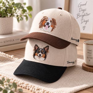 May include: Two baseball caps stacked vertically. The top cap is beige with a brown brim and an embroidered dog face, featuring the text Barney with a paw print. The bottom cap is beige with a black brim, an embroidered dog face, and the text Tommy with a bone.