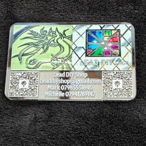 May include: A rectangular business card featuring a green horse illustration, a multi-colored geometric stained glass pattern, and the text Lead DIY Shop. It includes the email Leaddiyshop@gmail.com, names Mark and Michelle, phone numbers, and two QR codes.