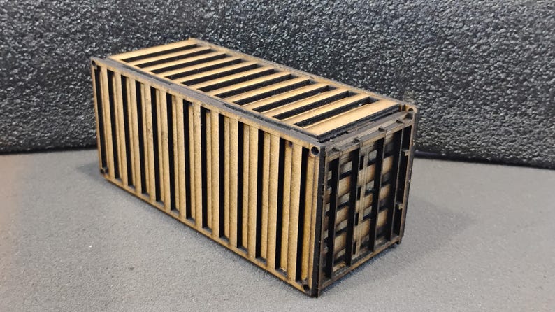 Może przedstawiać: Drewniany model kontenera transportowego z czarnymi detalami. Kontener jest zamknięty i ma realistyczny design.
