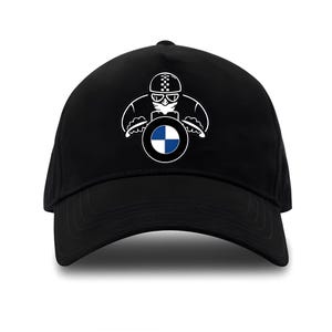 Può includere: Cappellino da baseball nero con una grafica bianca di una persona con casco che guida una moto con il logo BMW sul davanti.