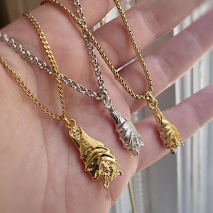 May include: Three bat pendant necklaces in gold and silver tones. The pendants are detailed with textured wings and bodies, suspended from delicate chain necklaces. The necklaces are displayed against a soft, blurred background.