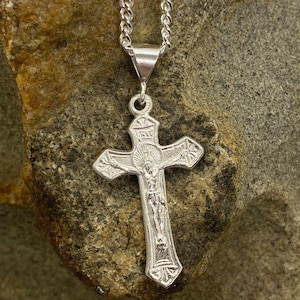 May include: A silver chain necklace with a silver crucifix pendant. The crucifix features a detailed depiction of Jesus Christ.