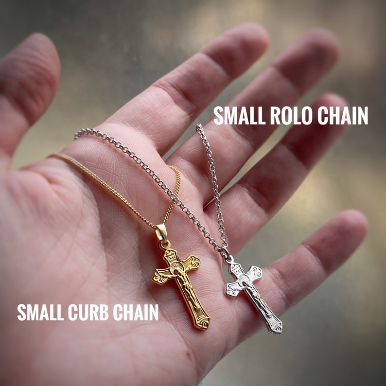 Pu&ograve; includere: Due collane in oro e argento con ciondoli a forma di crocifisso. La collana in oro &egrave; una piccola catena a curb e la collana in argento &egrave; una piccola catena rolo. Il testo "SMALL CURB CHAIN" &egrave; sotto la collana in oro e il testo "SMALL ROLLO CHAIN" &egrave; sopra la collana in argento.