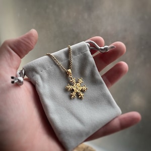 May include: A gold snowflake pendant necklace in a gray velvet pouch.