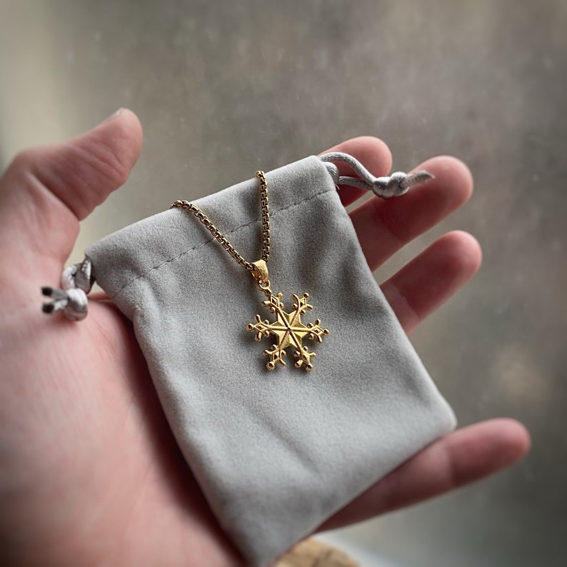 May include: A gold snowflake pendant necklace in a gray velvet pouch.