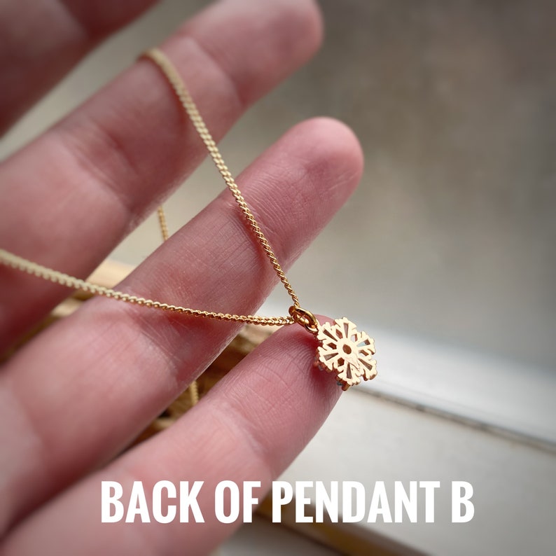 K&ouml;nnte beinhalten: Die R&uuml;ckseite einer goldenen Schneeflocken-Anh&auml;nger-Kette. Der Anh&auml;nger ist ein zartes, filigranes Design.