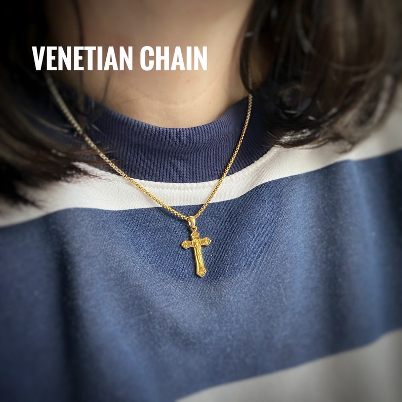 Pu&ograve; includere: Una collana a catena veneziana dorata con un ciondolo a croce dorato. La catena &egrave; sottile e delicata, e la croce &egrave; semplice ed elegante.