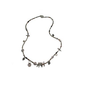 May include: A silver necklace with black and brown beads and various silver charms, including a small silver pot, a cross, and a star.
