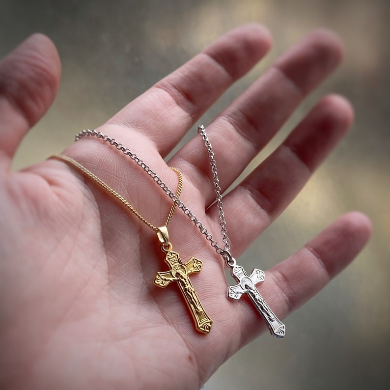 Pu&ograve; includere: Due collane d'oro e d'argento con ciondoli a forma di crocifisso. La collana d'oro presenta un crocifisso dettagliato con una figura di Ges&ugrave; Cristo. La collana d'argento ha un crocifisso pi&ugrave; semplice.