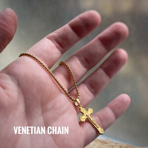 Pu&ograve; includere: Una collana con catena dorata e ciondolo a forma di croce dorata. La catena &egrave; una catena di stile veneziano. La croce ha un design dettagliato con una figura di Ges&ugrave; Cristo.