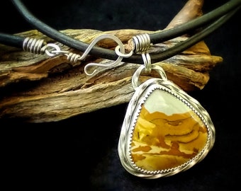 May include: A silver pendant necklace with a brown and white agate stone set in a silver wire wrapped bezel. The necklace is on a black leather cord with a silver clasp.