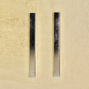 Könnte beinhalten: Zwei silberne Metallstäbchen-Ohrringe. Die Ohrringe sind schlicht und minimalistisch.