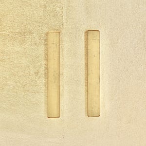 Può includere: Due barre verticali in legno marrone chiaro su uno sfondo beige chiaro.