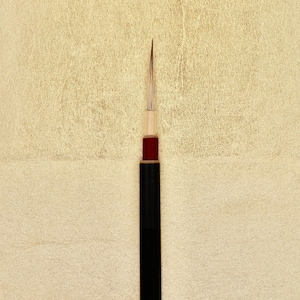 Peut inclure: Un pinceau de calligraphie noir et rouge avec une pointe pointue et un manche en bois.